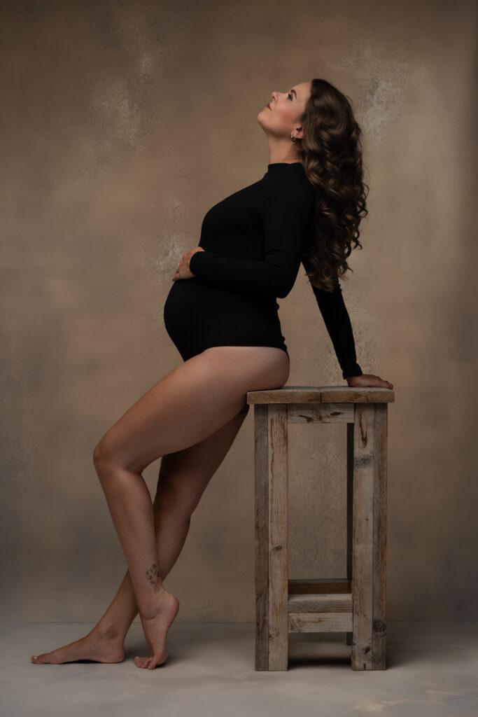 Stijlvolle zwangerschapsfotoshoot door Yvonne van Fotostudio ShootMe, met een witte kanten jurk en een minimalistische nude achtergrond.