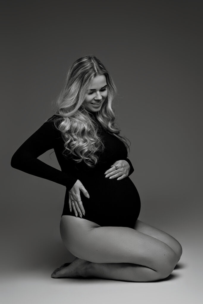 Minimalistische zwangerschapsshoot in studio Heemskerk met zwangere vrouw in zwarte bodysuit