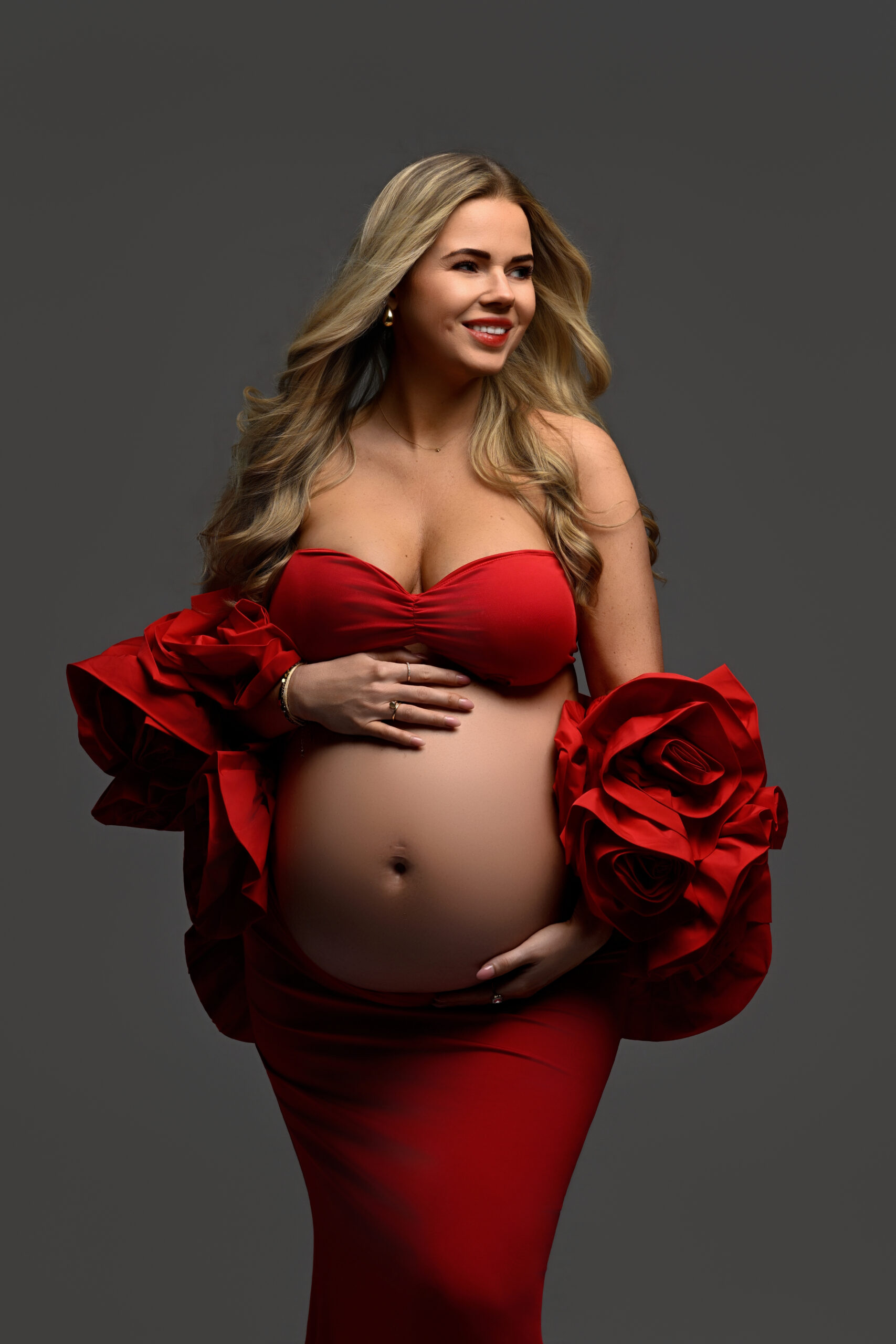Luxe zwangerschapsshoot in studio in Heemskerk met zwangere vrouw in rode couture jurk